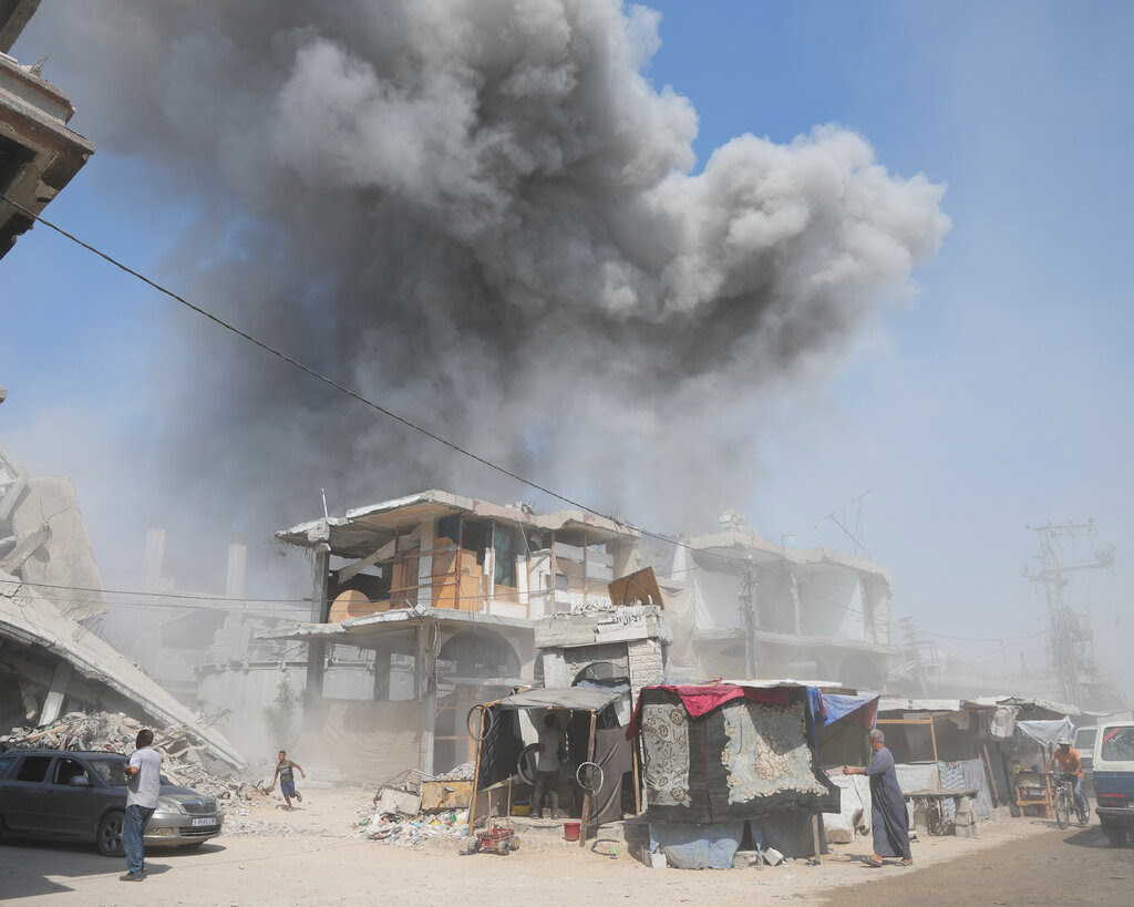 A large smoke cloud over damaged buildings.