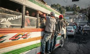 Pasajeros se aferran al exterior de un autobús en las calles de Puerto Príncipe.