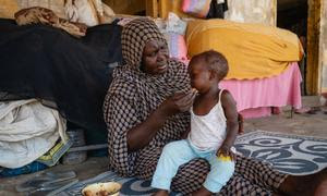 Una mujer da de comer a un niño en una escuela utilizada como punto de encuentro para desplazados en Puerto Sudán.