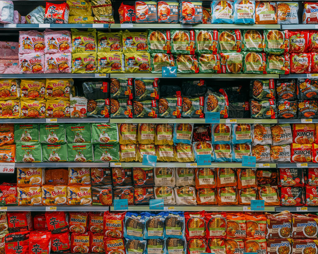 A well-stocked shelf of various brands of instant noodles and ramen at H Mart.