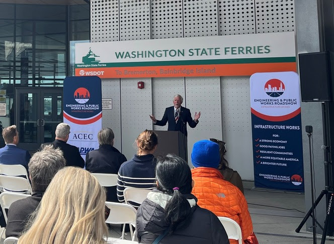 Person speaking behind a podium at Colman Dock in Seattle