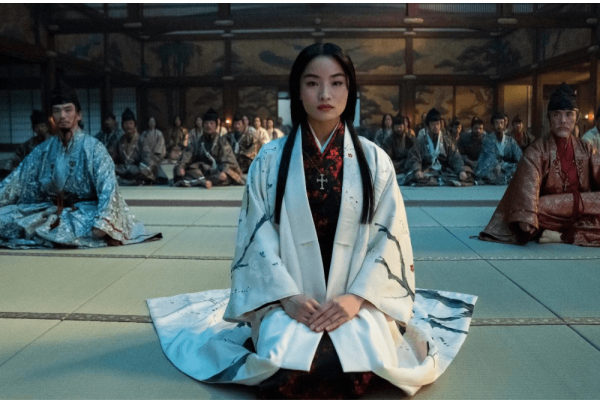 Shōgun character Toda Mariko wears white and kneels with her hands clasped in her lap. 