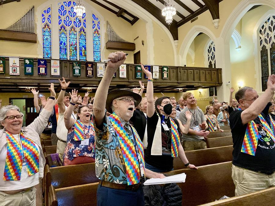 People gather in the First United Methodist Church in Charlotte N.C. for a sing-along. Many of the people gathered are wearing rainbow patterned sash around their necks.