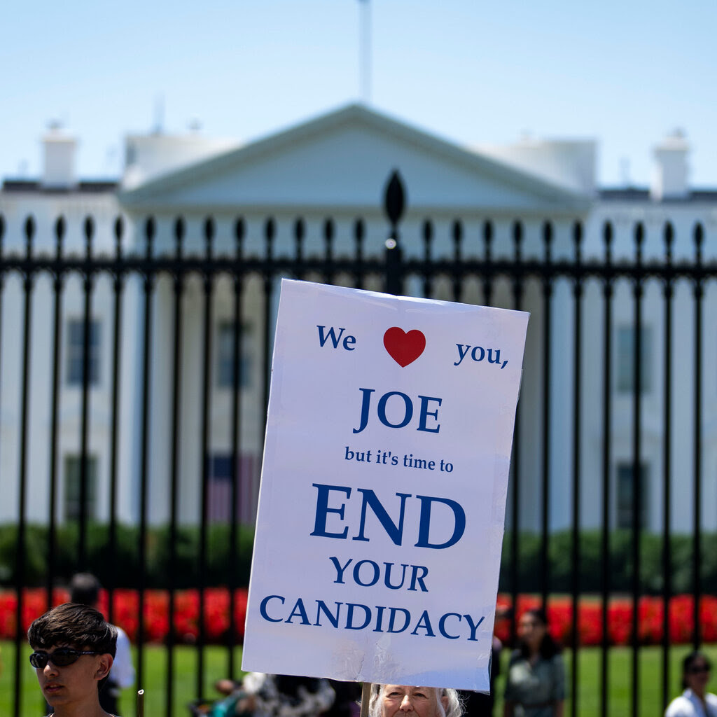 A sign held up outside the White House reads: “We love you, Joe, but it’s time to end your candidacy.”