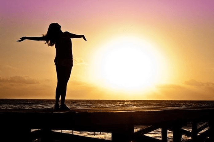 Silhouette of a woman spread arms near ocean