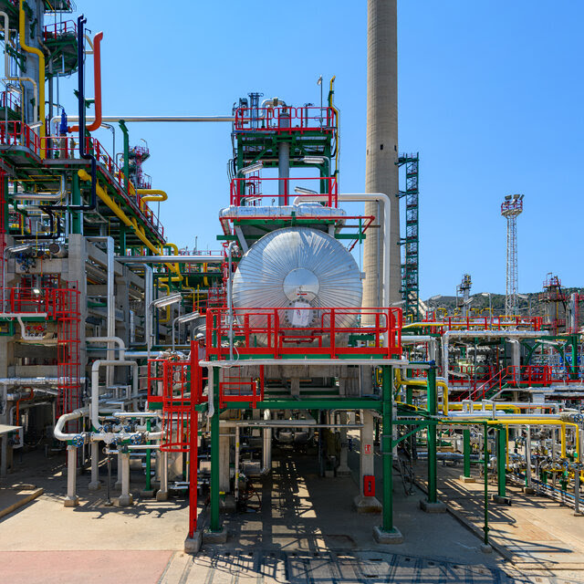 A large refinery with pipes and stairs, colored in green, red and silver. 