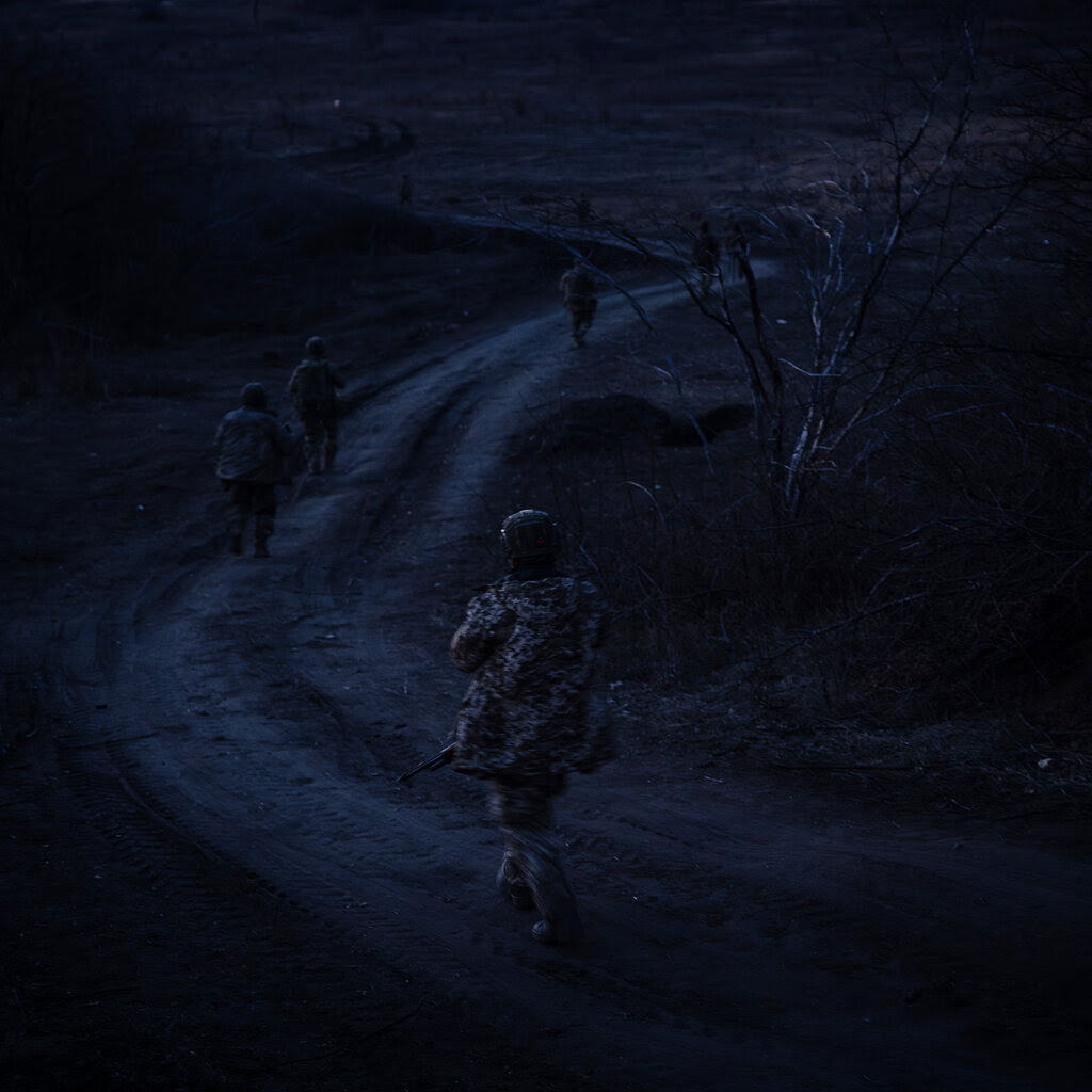 Soldiers walking on a road in low light condtions.