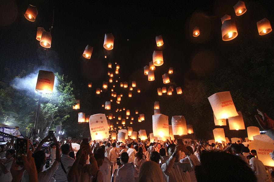 A crowd of people releasing paper lanterns into the sky.