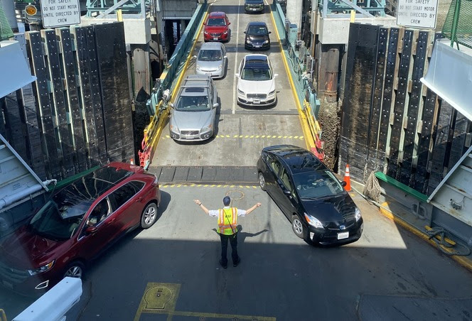 Vehicles entering ferry with a crewmember directing traffic on the car deck 