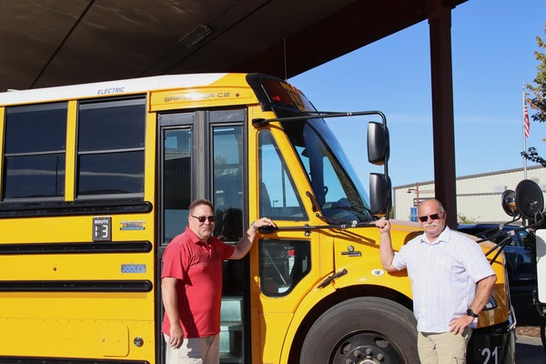 Two Walla Walla Public Schools administrators pose for a picture with the district's new electric bus.