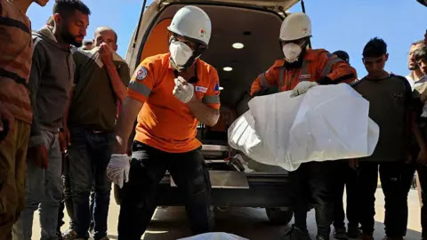 Getty Images Civil defense teams carry the body of a Palestinian following an Israeli airstrike on residential areas in central Khan Yunis, southern Gaza, on May 23, 2025.