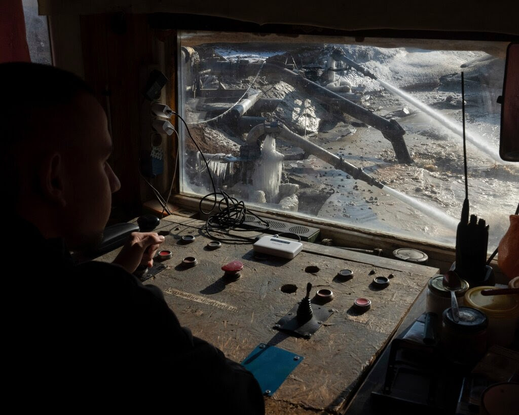 An operator at the controls of a machine looking through a small window.