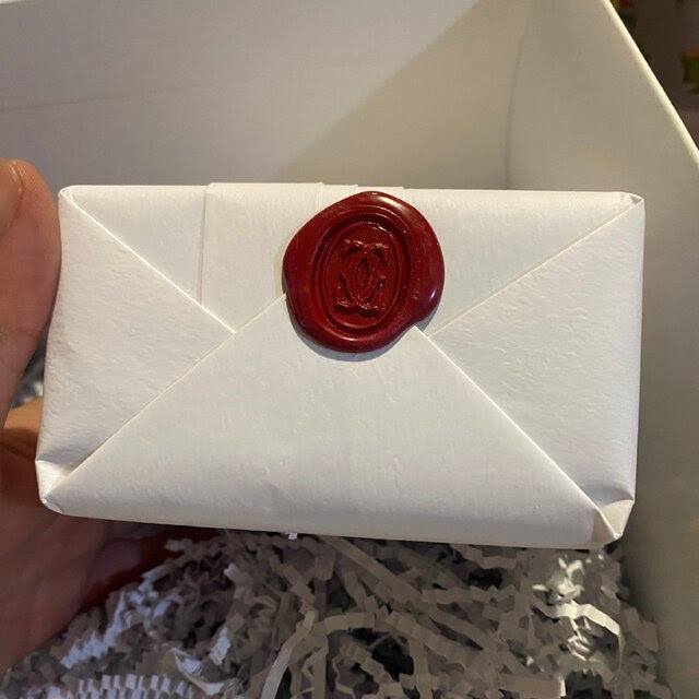 A wax seal displaying the Cartier logo is on the wrapping of a boxed item.