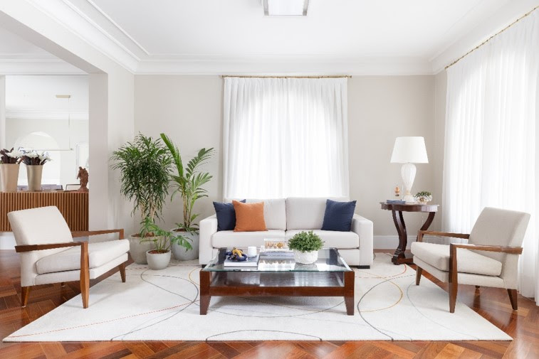 A cor branca escolhida para a base tonal do estar, adjacente à sala de jantar, trouxe uma importante base neutra onde o piso revitalizado poderia brilhar como item decorativo. Ademais, o sofá e o tapete da Punto e Filo criam um lounge aprazível para conversas, receber visitas e claro, descanso. Projeto: Daniela Funari | FOTO: Julia Novoa