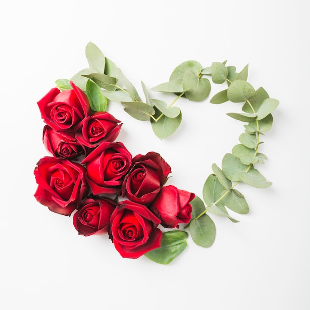 Bezpłatne zdjęcie kierowy kształt robić z róża kwiatem i gałązką na białym tle