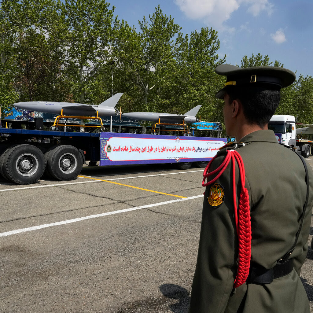 A line of soldiers facing a flatbed truck with drones on it.