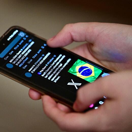 A Brazilian user of the social network X, formerly Twitter, browses posts on a cell phone in Brasilia on August 31, 2024. Despite the court order to block X throughout Brazil, issued by Supreme Court judge Alexandre de Moraes, some users are still able to access the social network's pages in the country. (Photo by EVARISTO SA / AFP)