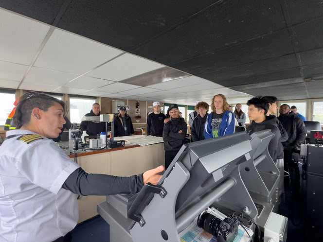 Several people in a ferry's wheelhouse