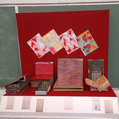 A display of marbled paper and book bindings in a glass case