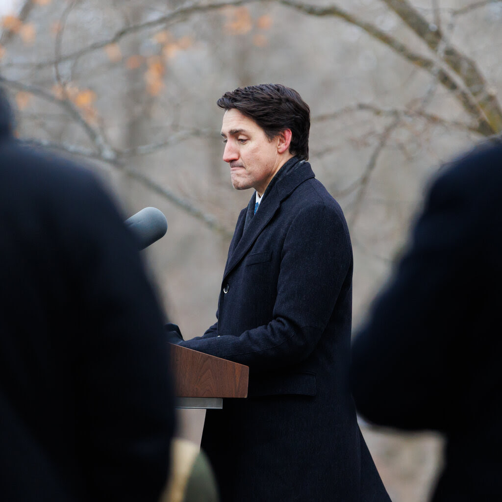 Canadian Prime Minister Justin Trudeau standing at a lectern and making a frowning face.