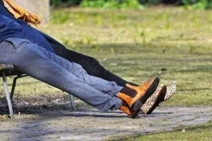 Legs extended from two people sitting on a park bench