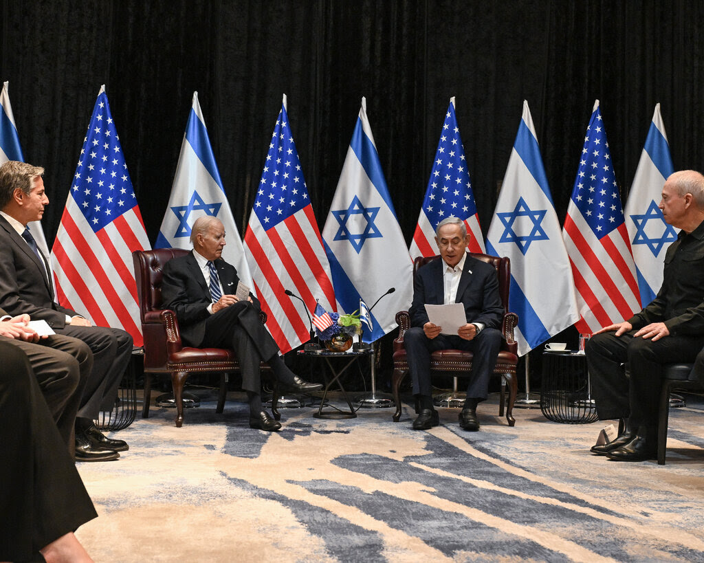 President Biden, Prime Minister Benjamin Netanyahu and other officials are seated in a circle in front of American and Israeli flags.