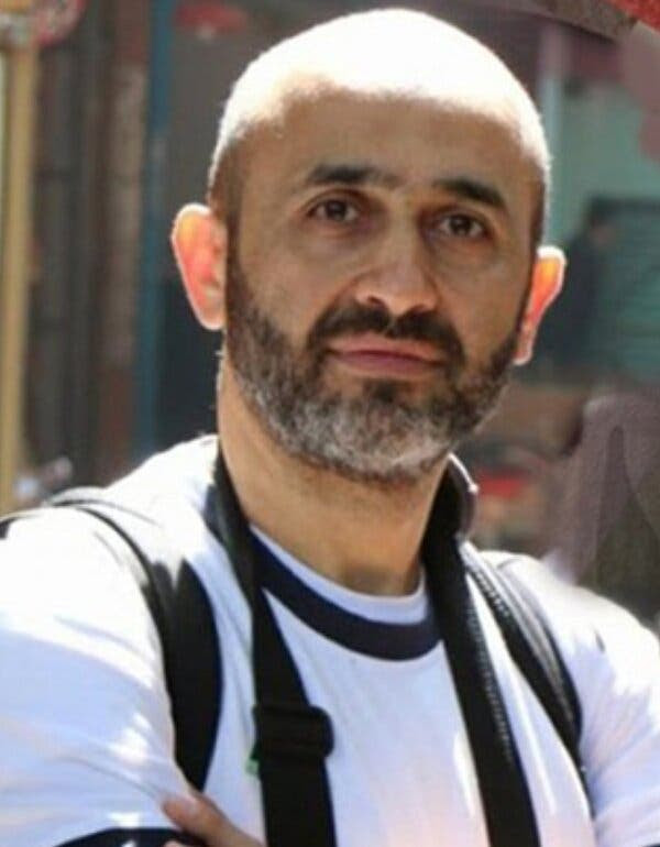 Amer Al-Shawa wearing a white T-shirt with a black collar.