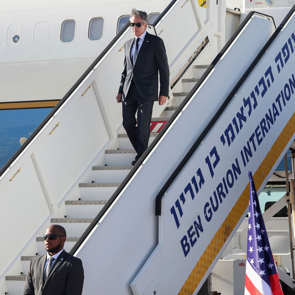 Antony Blinken walking down steps, off a plane. In Hebrew and English, the stairs are labeled “Ben Gurion International Airport.” 