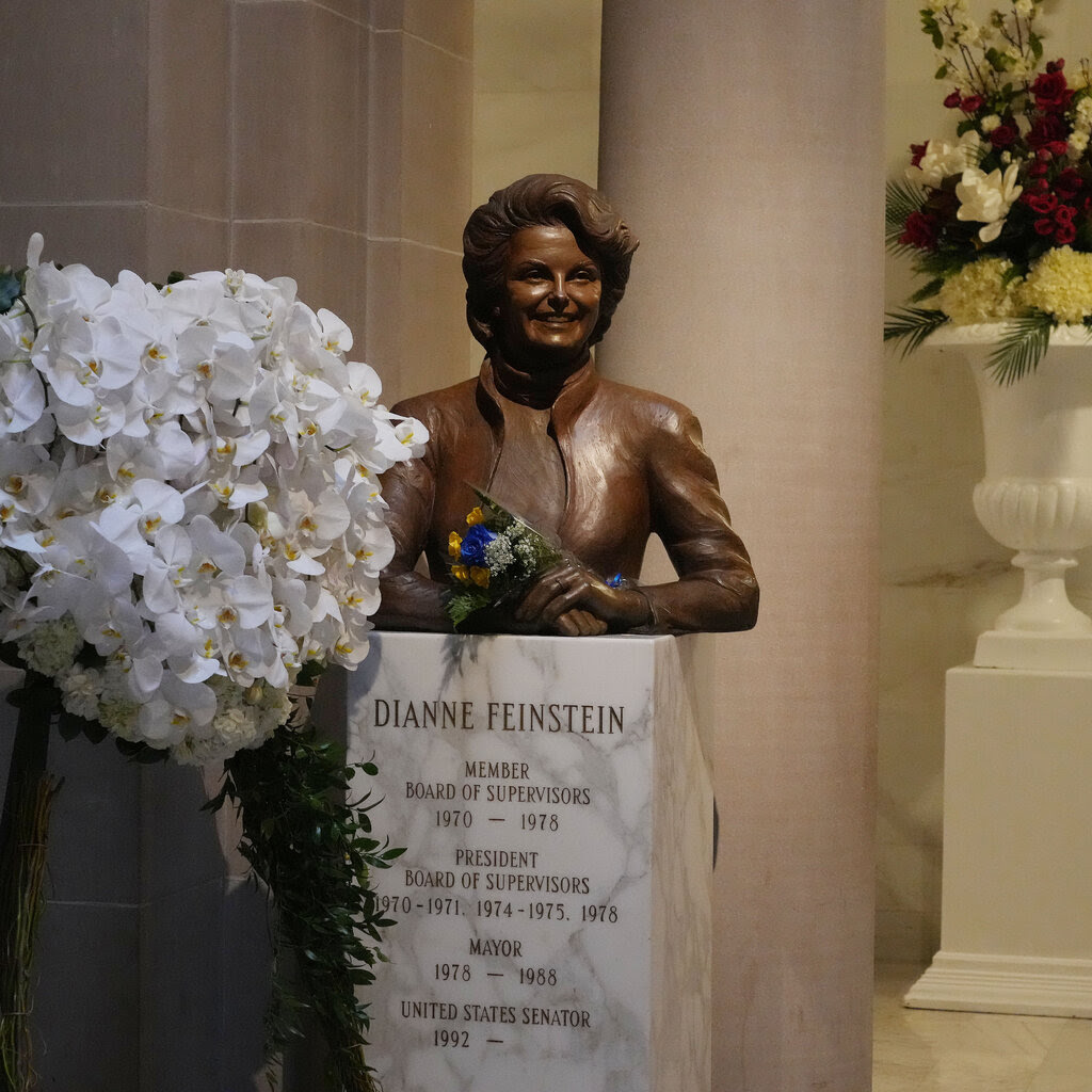 A bust of Dianne Feinstein is adorned with flowers. 