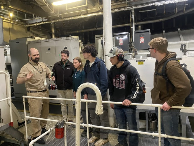 Ferry crewmember talks to students in the engine room