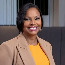 Smiling WOC with a red shirt, black jacket and red lipstick