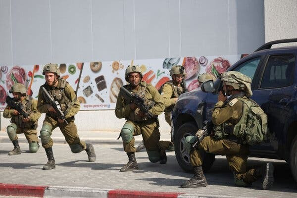 Armed soldiers kneeling near a truck.