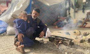 Un hombre y un niño sentados junto a una pequeña hoguera en Nuseirat, en el centro de Gaza.