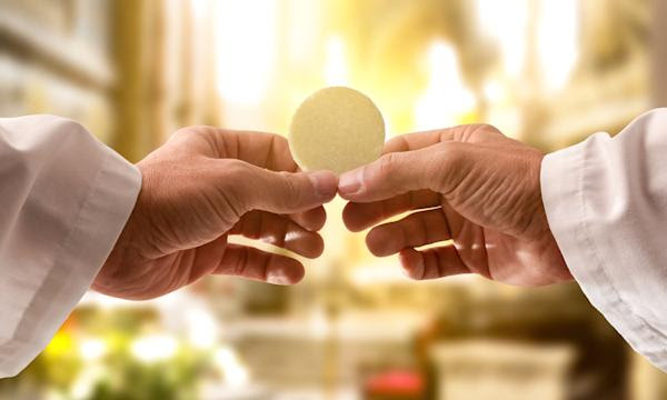 1616. Le Christ se manifeste à Cambrai : Miracle Eucharistique Hostie_Mains_Pre_tre_Lumie_re___Shutterstock_Davizro_Photography