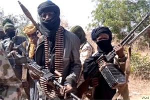Several men are standing together with their faces covered, holding heavy artiliary.