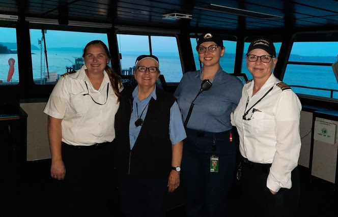 Four ferry crewmembers pose for a photo in the wheelhouse