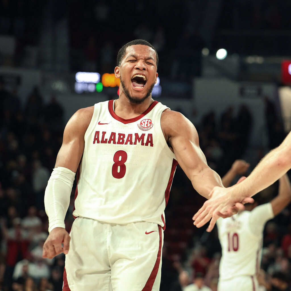 Chris Youngblood, in a white jersey printed with “Alabama” and the No. 8, yells as he slaps the hand of someone outside the frame.