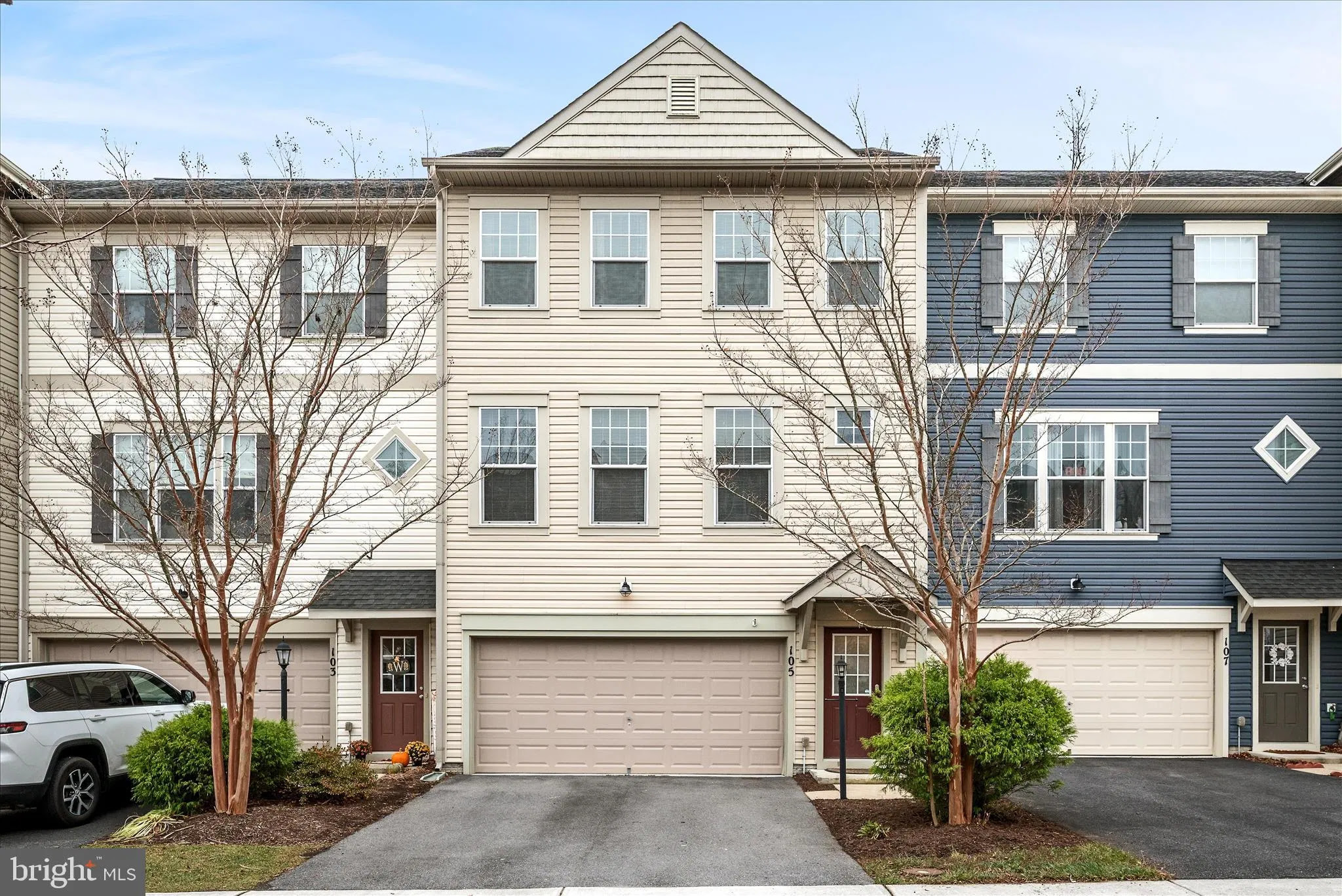 Modern beige three-story townhome with double garage and clean landscaping
