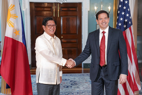 Secretary Rubio and Philippine President Marcos, Jr. shaking hands while standing beside U.S. and Philippine flags.