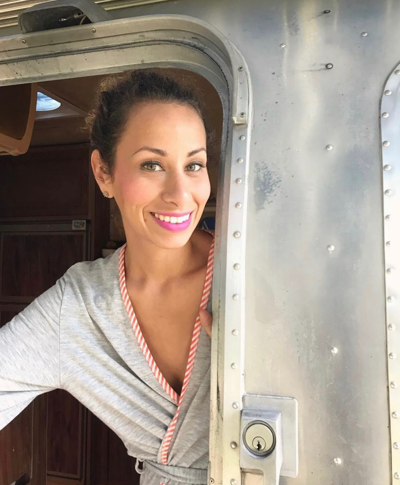 Jules De Jesús Fritz coming out of vintage Airstream camper in grey bathrobe 