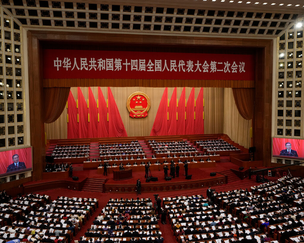 An auditorium with red curtains, red carpet and red Chinese flags. 