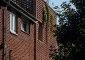 La separación de los ladrillos suaviza la forma imponente de la casa y permite que la vegetación se entrelace con la estructura.
