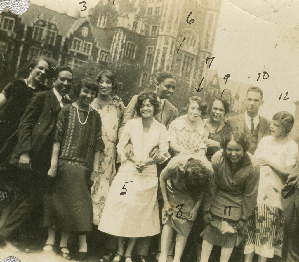 A black-and-white photograph of 13 Black people on a rooftop. There are numbers written on the image.