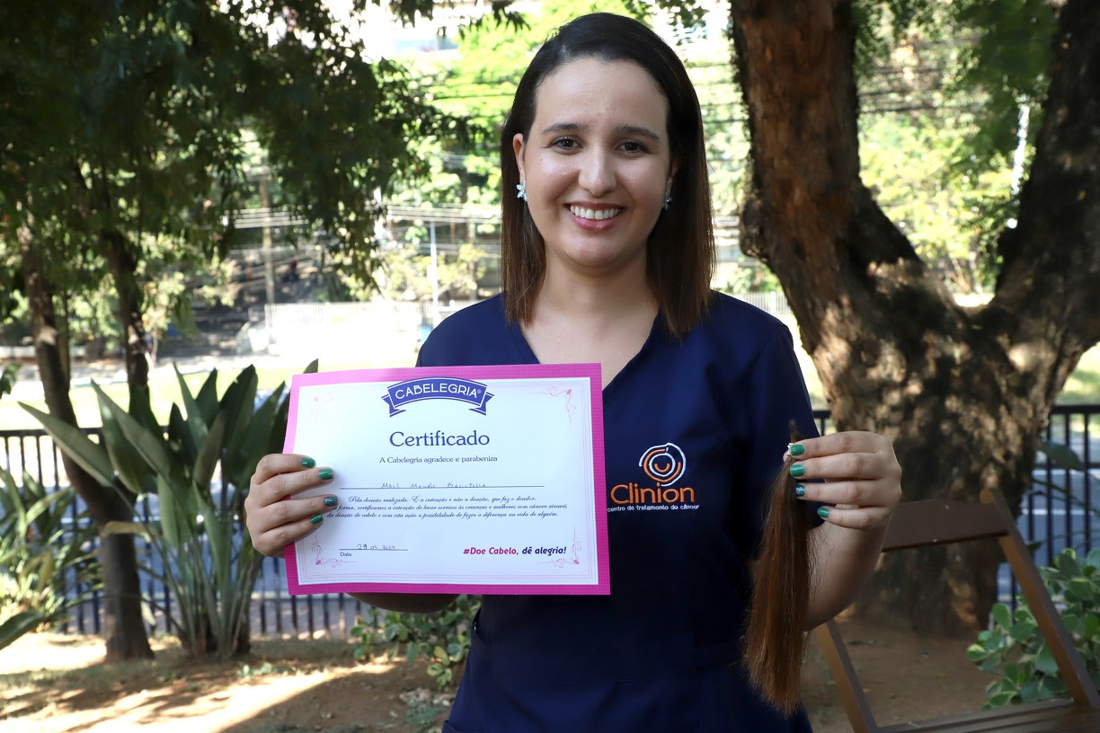 Enfermeira Maéli Mendes Batistella com seu certificado de doação à organização Cabelegria 