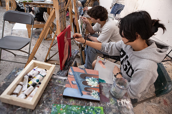 Students painting on easels in a studio