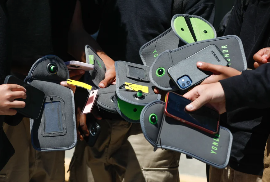 Students hold magnetic pouches to lock their phones in