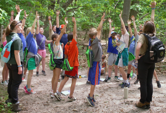 Young students excited raised their hands in a forest education class