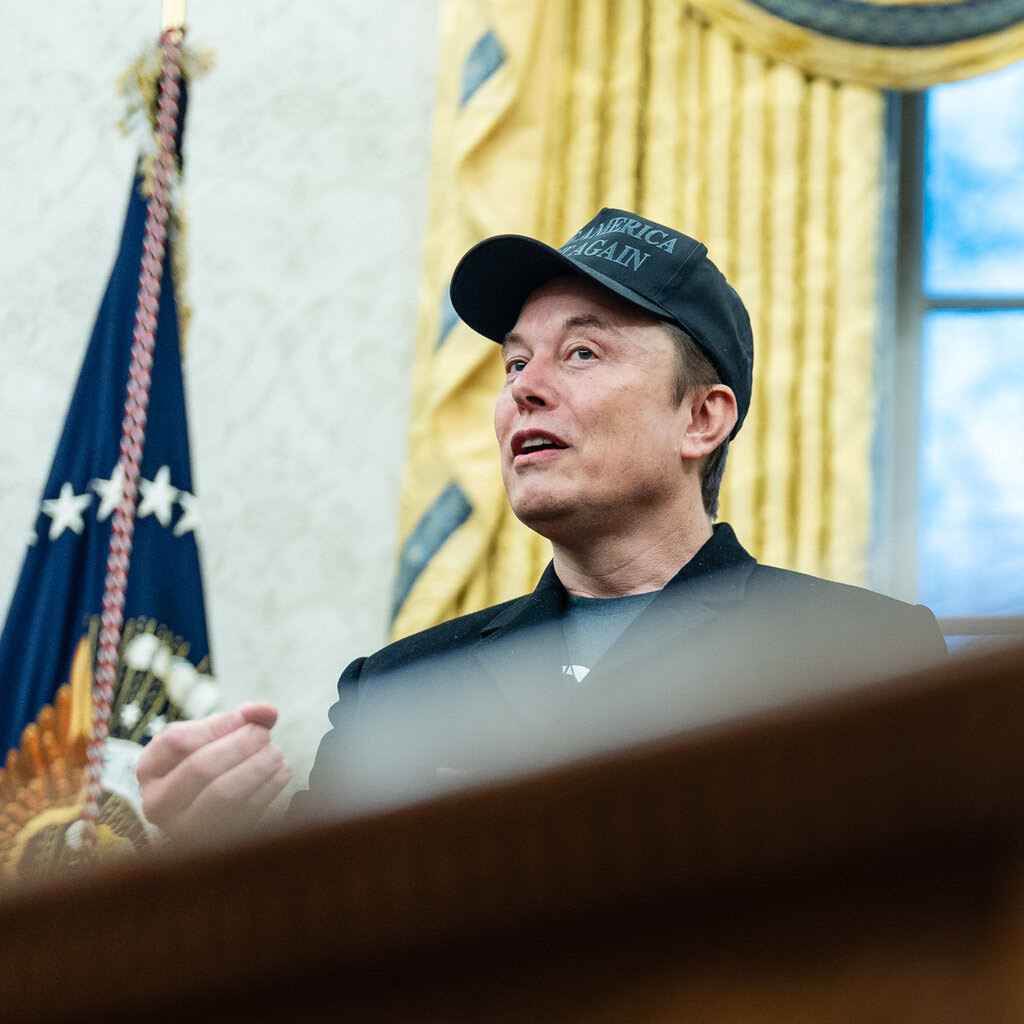 Elon Musk in a black hat in the Oval Office