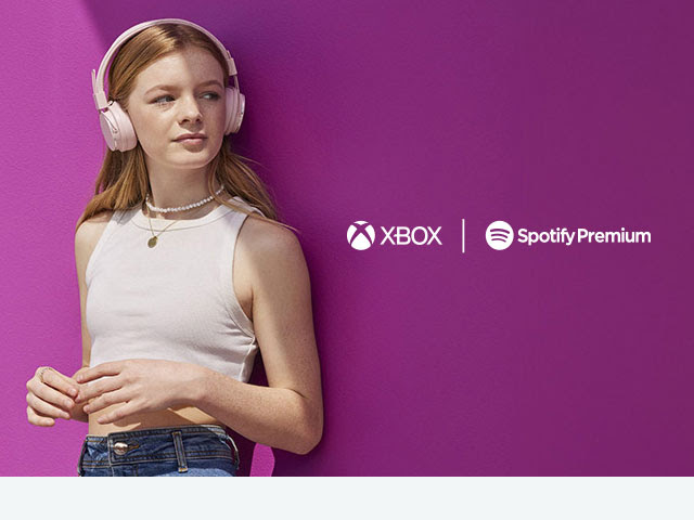 Xbox and Spotify Premium, A woman stands and listens to music on headphones.