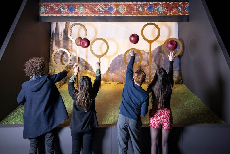 A group of people holding objects up to a wallAI-generated content may be incorrect.